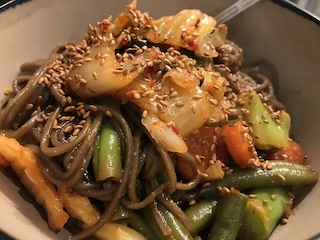 A bowl of noodles with Chinese stir-fried veggies on top