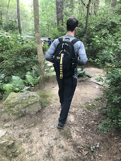 a man carrying a backpack walks through the woods