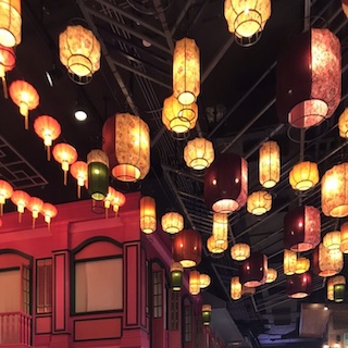 many glowing paper lanterns light the facade of a red building