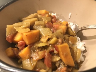 A bowl of chopped veggies with indian spices served on rice