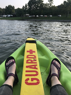 a person sits in a kayak serving as lifeguard as people swim