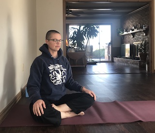 person sitting on floor with legs crossed, meditating