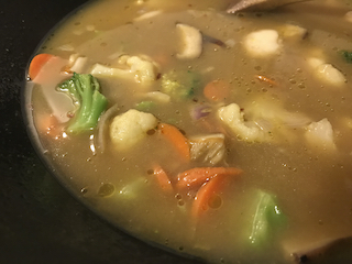 wok containing aromatics and frozen veggies cooking on the stove