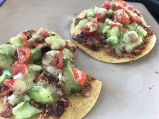 a plate with two tostadas topped with tomatoes and peppers