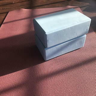 two light blue yoga blocks stacked upon a purple yoga mat